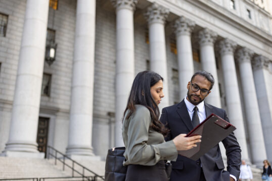 two government workers discussing in front of a government building